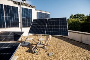Man carries solar panel while installing solar plant of a rooftop of his property. Renewable energy for self consumption concept. Idea of installing panels for households